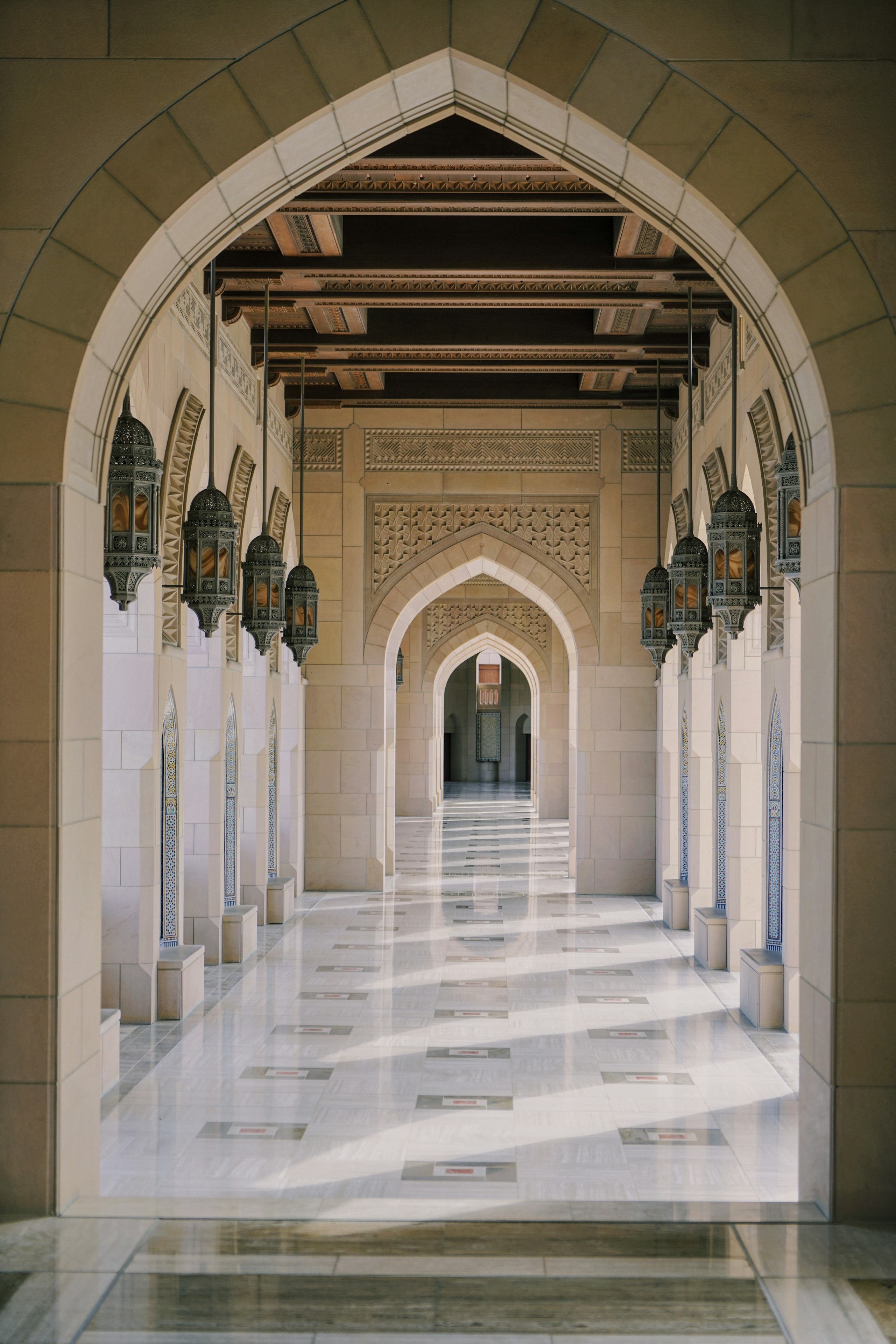 A long arcade of stone arches lit by afternoon sun
